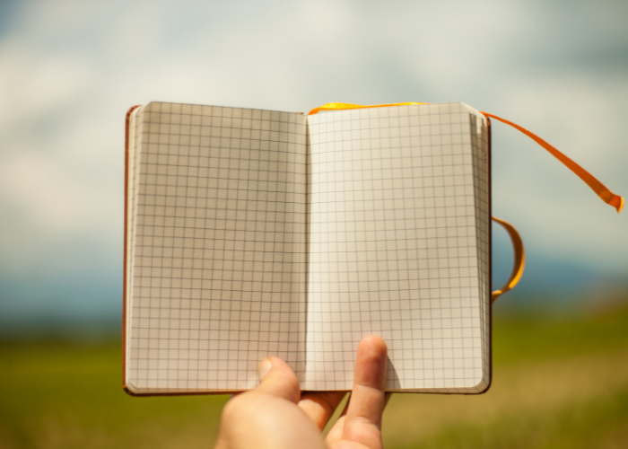 A blank journal with grid lines, held up to the sky